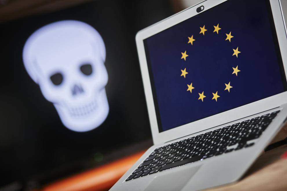 Boj proti terorističnim vsebinam na spletu (Foto: prenosni računalnik z evropsko zastavo na ekranu in sliko lobanje na črni podlagi v ozadju)