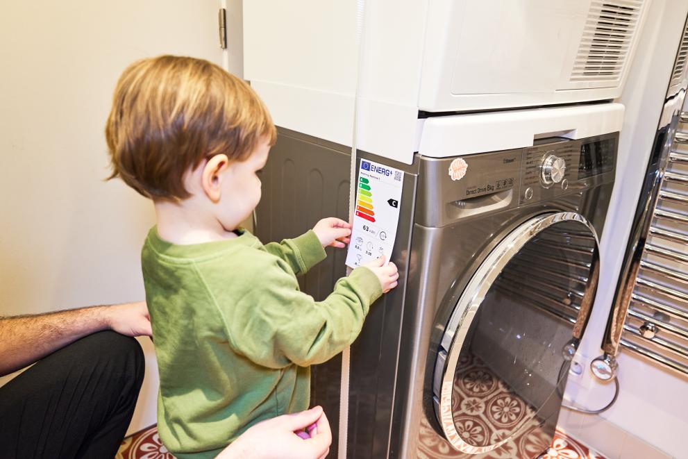 Krepitev vloge potrošnika za zeleni prehod (Foto: Malček lepi nalepko o energijski učinkovitosti na pralni stroj)