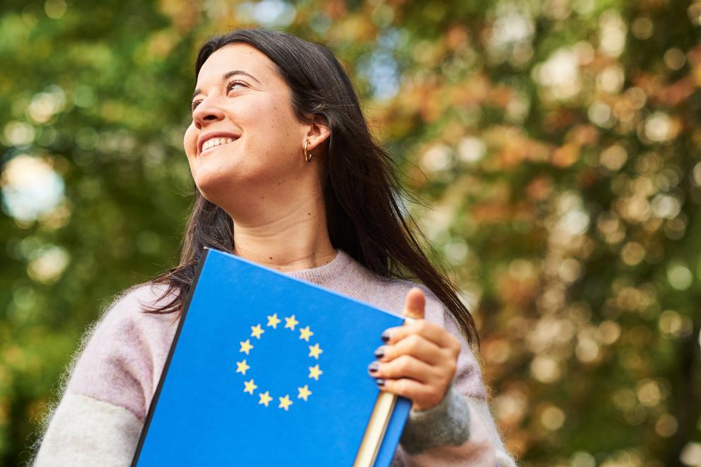 14 novih zavezništev evropskih univerz (Foto: mlada ženska, ki v roki drži mapo z logotipom EU)
