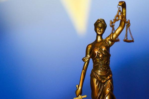 Nov sveženj odločb o kršitvah zakonodaje EU (Foto: bronsti kip Themis, boginje pravičnosti, v ozadju pa delček evropske zastave)