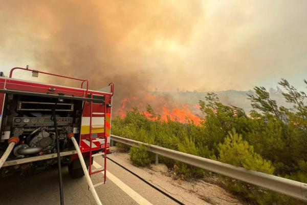 (Foto: obcestni požar v Grčiji. Na cesti gasilsko vozilo)