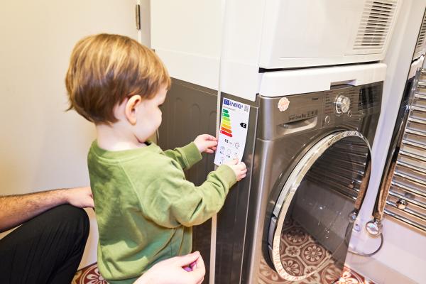 Krepitev vloge potrošnika za zeleni prehod (Foto: Malček lepi nalepko o energijski učinkovitosti na pralni stroj)