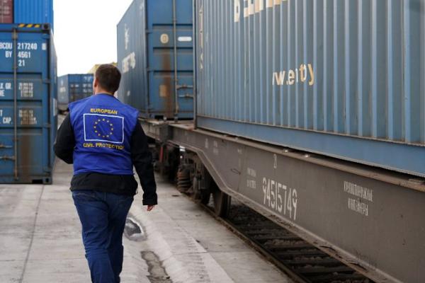 Nova serija generatorjev za Ukrajino (Foto: delavec med kontejnerji generatorjev oblečen v jopiž z evropsko zastavo in pripisom evropska humanitarna in zivilna zaščita na hrbtu)