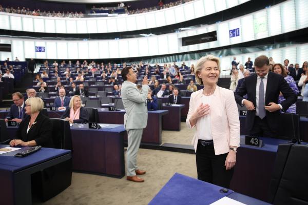 Na novo izvoljena predsednica Evropske komisije Ursula von der Leyen, vidno ganjena, stoji v Evropskem parlamentu, za njo pa stojijo evropski poslanci.  em 